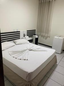 Cama blanca grande en habitación con teléfono en Oft Neve's hotel en Goiânia