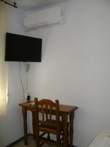 Elle comprend un bureau avec une chaise et une télévision murale. dans l'établissement Hostal Residencia Pasaje, à Novelda