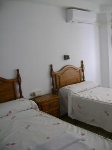sypialnia z 2 łóżkami i stolikiem nocnym oraz 2 łóżkami rozmiarowymi w obiekcie Hostal Residencia Pasaje w mieście Novelda