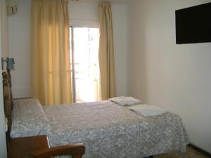 a bedroom with a bed with a television and a window at Hostal Residencia Pasaje in Novelda