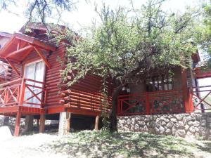 Cabaña de madera con árbol y pared de piedra en Complejo Arlington Village en Cortaderas