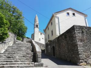 un ancien escalier en pierre avec une église et une tour dans l'établissement Apartmaji in sobe Odlična hiša Štanjel, à Štanjel