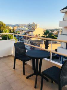 una mesa y sillas en un balcón con vistas en 21 Suites Deluxe Stay Near The Airport, en Markopoulo