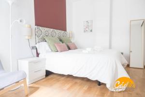 ein weißes Schlafzimmer mit einem weißen Bett und einem Stuhl in der Unterkunft Apartamento Caleta - FREE PARKING by Cadiz Time in Cádiz