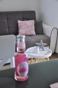 a bottle of drink on a table next to a couch at Apartmani Carnizza in Ražanac