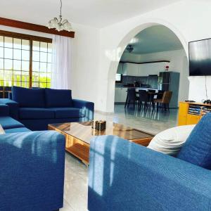 a living room with blue couches and a table at Villa Kapistris Dyo in Coral Bay