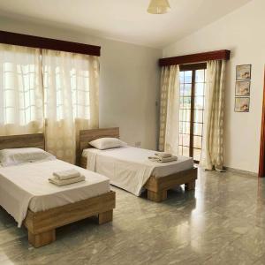 two beds sitting in a room with windows at Villa Kapistris Dyo in Coral Bay