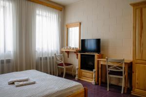 a bedroom with a bed and a television and a desk at Гостерія"Old Town" in Kamianets-Podilskyi