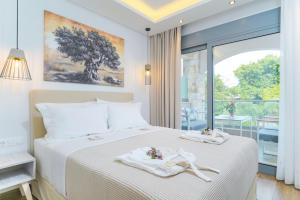a bedroom with a white bed with a large window at Maria Elena Suites in Limenas