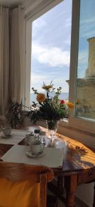 un tavolo con un vaso di fiori e una finestra di La Casetta e Mammà a Positano
