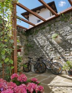 zwei Fahrräder, die an einer Steinmauer mit Blumen geparkt sind in der Unterkunft Apartmaji in sobe Odlična hiša Štanjel in Štanjel