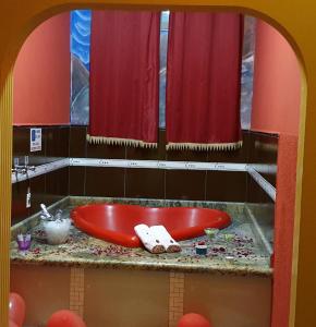 SP Hotel & Motel في موغي ميريم: حوض استحمام احمر في حمام مع ستائر حمراء