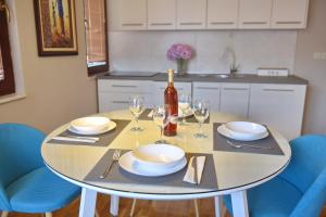 a table with plates and glasses and a bottle of wine at SI Apartments Ohrid with free parking in Ohrid