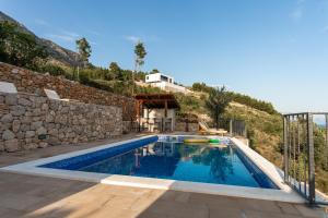 a swimming pool in a villa with a stone wall at Exclusive Villa Almissa with swimming pool and sea view in Lokva Rogoznica