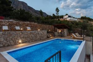 a swimming pool in front of a stone wall at Exclusive Villa Almissa with swimming pool and sea view in Lokva Rogoznica