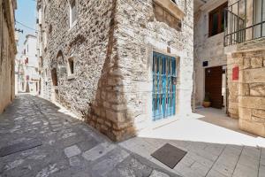 an alley with a stone building with a blue door at Villa Kudelik - Stone Story in Trogir