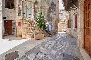 a courtyard with a potted plant in an alley at Villa Kudelik - Stone Story in Trogir