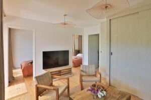 een woonkamer met een televisie en een tafel en stoelen bij Les Cabanes de la Fontaine in Lacoste