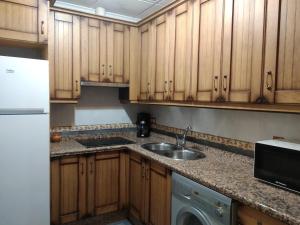 a kitchen with wooden cabinets and a sink and a dishwasher at El Ventorrillo Grande in Riópar
