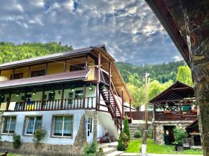 une grande maison avec un escalier en face de celle-ci dans l'établissement Pensiunea Andra, à Albac