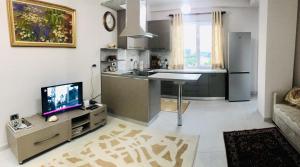 a living room with a kitchen and a tv in it at Cappuccino Apartment in Lezhë
