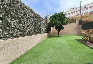 a patio with a tree and a wall with grass at Vila Azul in Sesimbra