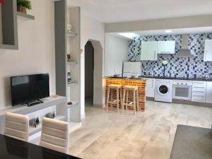 a kitchen with white cabinets and a tv in it at Casa La Mimbrera in Las Navas del Marqués