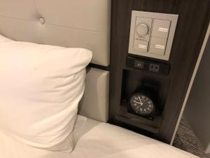 a clock next to a bed with a pillow at Via Inn Nagoya Station Tsubaki-cho in Nagoya