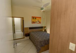 1 dormitorio con cama y espejo. en Res. Calliandra Apto 201, en Bombinhas
