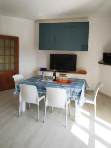 a dining room table with white chairs and a television at CONERO APARTMENT in Castelfidardo