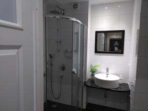 a bathroom with a glass shower with a sink at Apartament Wrocław przy Rynku in Wrocław