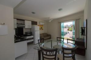 cocina y sala de estar con mesa de cristal y sillas en Res. Calliandra Apto 101, en Bombinhas