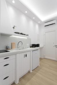 uma cozinha com armários brancos, um lavatório e uma porta em Hora Seaside Suites em Naxos Chora