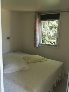 1 cama blanca en un dormitorio con ventana en Nature Monchy, en Campneuseville