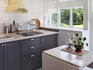uma cozinha com armários azuis, um lavatório e janelas em Holiday home Veddige II em Veddige