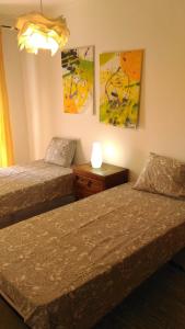 2 camas en una habitación con pinturas en la pared en casa da teresa, en Olhão