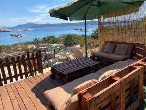 una terraza de madera con sofá y sombrilla en B&B Il Corallo en La Maddalena
