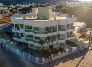 un edificio blanco con palmeras delante en Res Calliandra Apto 102, en Bombinhas