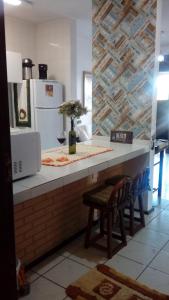 a kitchen with a counter with a refrigerator and a chair at LINDO AP CAPAO NOVO in Capão da Canoa