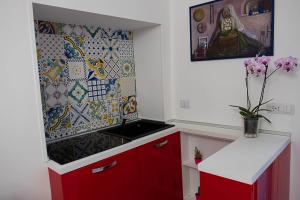 eine Küche mit roten Schränken und einer Mosaikwand in der Unterkunft Alma Cilento in Ascea