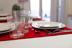 einen Tisch mit Tellern und Gläsern auf einer roten Serviette in der Unterkunft Alma Cilento in Ascea