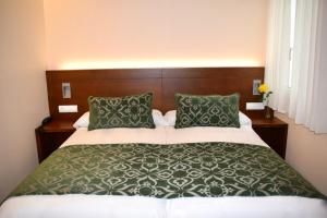 Un dormitorio con una cama grande con sábanas y almohadas verdes y blancas. en Mapoula PR Boutique en Santiago de Compostela