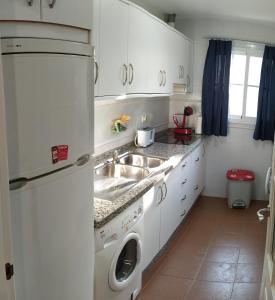 eine weiße Küche mit einer Spüle und einem Geschirrspüler in der Unterkunft Albatros Golf Costa Esuri Ayamonte Huelva in Ayamonte