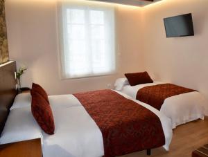 a hotel room with two beds and a television at Mapoula PR Boutique in Santiago de Compostela
