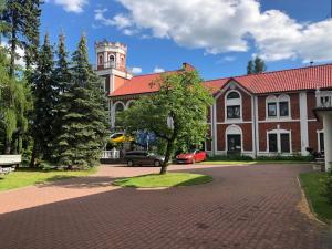 a building with a clock tower and a tree in front at Hotel Zameczek in Radomsko