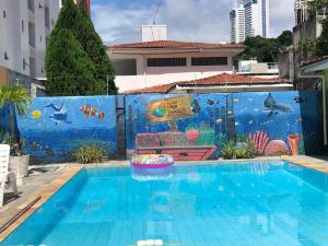 a swimming pool with a mural on a wall at Pousada Cabo Branco in João Pessoa