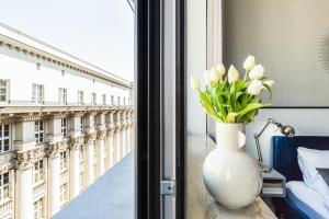wazon kwiatów siedzący na stole obok okna w obiekcie Wielopole17 Max Apartment with AC w Krakowie