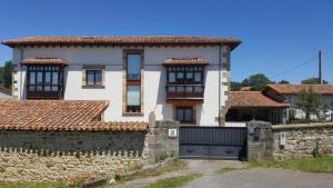 a large white house with a stone wall at FORJAS DE ORZALES in Orzales