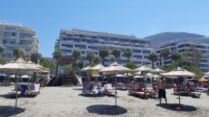 una spiaggia con ombrelloni e persone sedute sulla sabbia di G Balcony Apartment a Vlorë