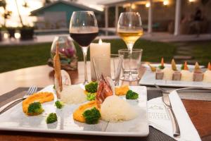 a plate of food on a table with wine glasses at Hôtel Raiatea Lodge in Uturoa